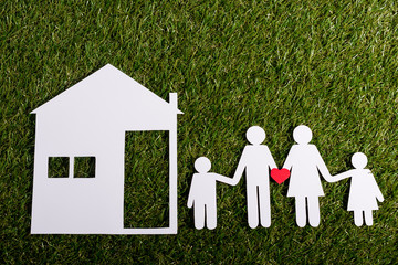 Paper cut of family near house on the artificial grass