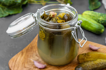 Pickles - canned fermented cucumbers in glass jar on dark background, horizontal orientation