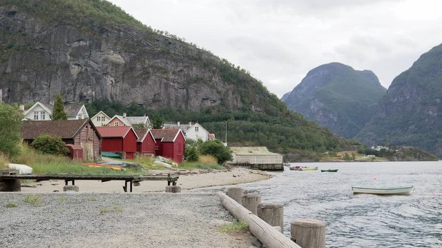 Typical Norwegian view to the fjord with red houses (rorbas) on the shore. Small fishing boats floating in the water.