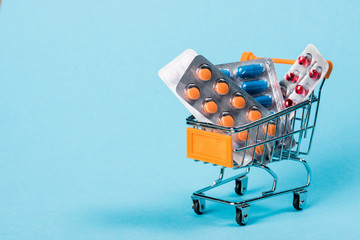 Pharmacy medicine concept. Shopping cart with pills and capsules