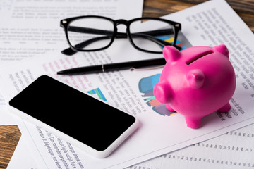Pink piggy bank, phone and documents on the table