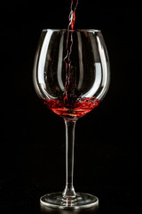 Red wine being poured in a wine glass on a dark background