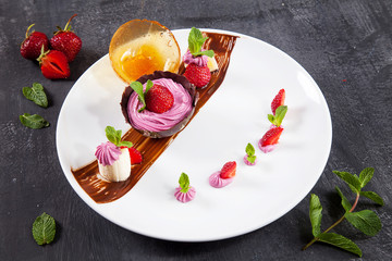 Close up view on tasty and cold strawberry ice cream in a chocolate bowl. Fresh dessert after lunch. Dark background. Food photo with sweets for menu or recipe