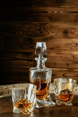 Two glasses of brandy or cognac and bottle on the wooden table