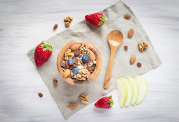 Healthy breakfast with muesli, almonds, blueberries, walnuts and strawberries on white background. Top view.