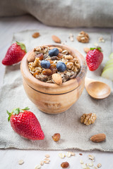 Healthy breakfast with muesli, almonds, blueberries, walnuts and strawberries on white background. Top view.