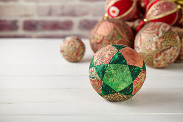 Patchwork puzzle balls and christmas decorations in basket on brick wall background