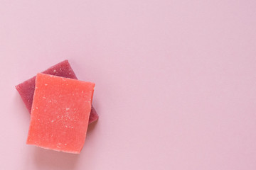 Multi-colored pieces of natural handmade organic soap on pink with place for text. Concept of hygiene, medicine, health care
