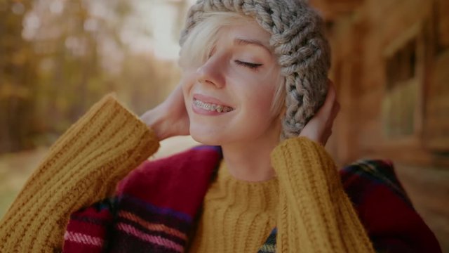 Young happy smiling hipster girl with orthodontic braces on her teeth wears knitted gray beanie hat. Stylish autumn outfit