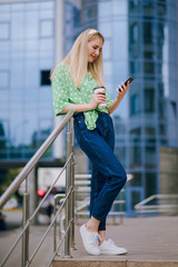 beautiful blonde drinking coffee near the mall