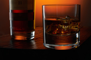 Old fashion whiskey on the rocks with a bottle
