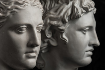 Gypsum copy of ancient statue Apollo and Diana head on dark textured background. Plaster sculpture face.