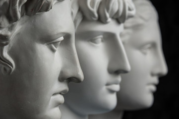 Gypsum copy of ancient statue Apollo, Antinous and Venus head on dark textured background. Plaster sculpture face.