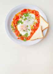Fried eggs with sliced tomatoes and parsley, top view. Healthy breakfast and lunch. Roasted eggs on the plate with copy space.