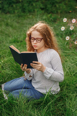 Obraz premium Little girl dreaming or reading a book in outdoors. Education concept.