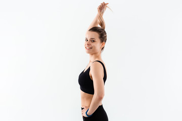 Young sporty blond woman in a black sportswear exercising isolated over white background.