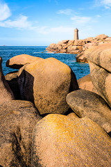 Fototapeta na wymiar The Ploumanac'h lighthouse, named Mean Ruz, on the Pink Granite Coast in northern Brittany on the municipality of Perros-Guirec, France, with large pink granite rocks in the foreground.