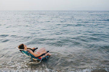 Naklejka premium woman sitting on a beach chair over the sea