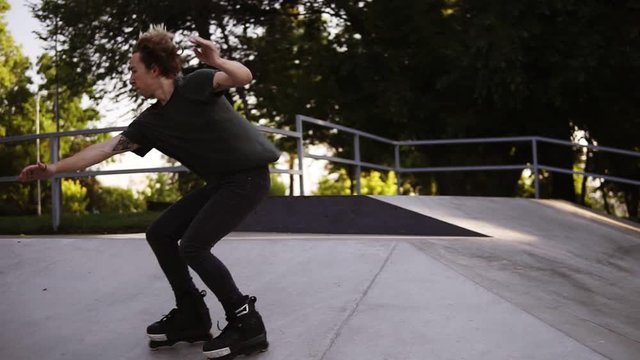 A man on rollers performs a trick on the ramp, makes a full turn in the air and landed on his feet. Modern, outdoor skate park in the middle of the city