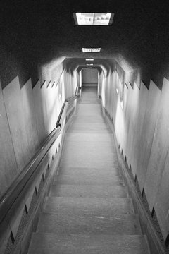 Dark corridor stairs. Going into the tunnel and  underground transportation.  Black and white photography in Milan, Lombardy, Italy, Europe.