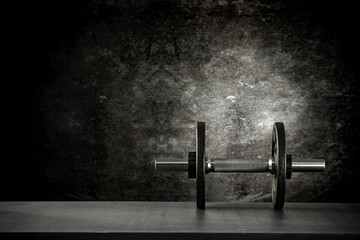 Dumbbell, barbell and workout in the gym. Copy space on black grunge wall and board background.