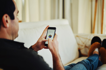 Close-up of a man sitting on sofa using smartphone
