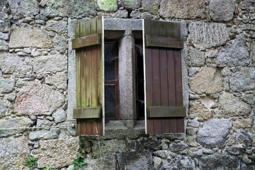 Window with old wooden shutters partially opened belonging to an old stone castle.