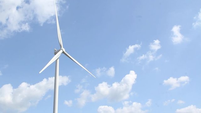 Energy turbine against a blue sky with white clouds - aligned left