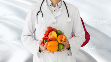Doctor is holding fruits and vegetables in hands with Japan flag background. National healthcare concept, medical theme.
