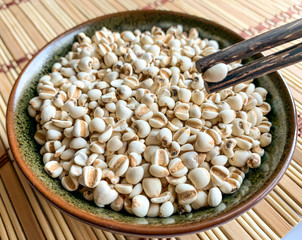 Job's Tears or Millet in a bowl and on a wooden chopstick placed on a wooden mat