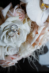 Wedding rings lie on a table next to a bouquet