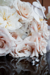 Wedding rings lie on a table next to a bouquet