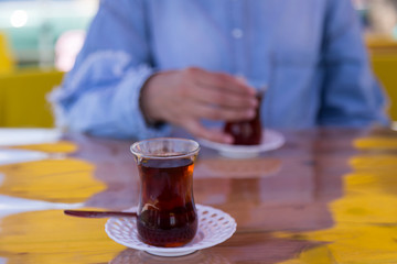 the woman hold the dark red color glass of tea on the wooden background.