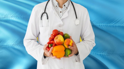 Doctor is holding fruits and vegetables in hands with Palau flag background. National healthcare concept, medical theme.