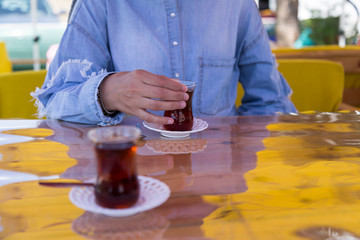the woman hold the dark red color glass of tea on the wooden background.