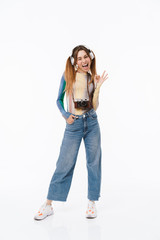 Full length photo of cheerful young girl wearing headphones showing ok sign while carrying retro camera