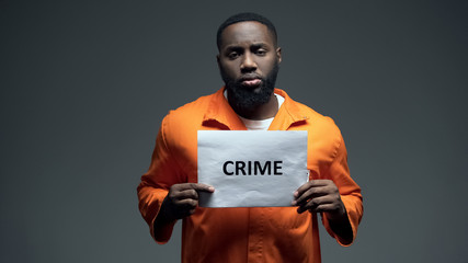 African-american prisoner holding crime sign, looking to camera, awareness