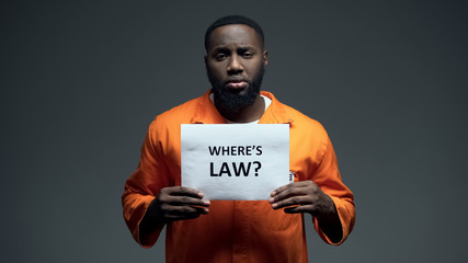 Afro-american prisoner holding where is law sign in cell, wrongly accused person