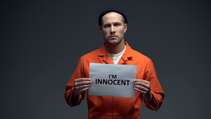 European imprisoned male holding I am innocent sign in cell, asking for justice