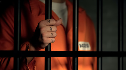 Hope word on imprisoned man fingers, holding jail bars, dream about freedom - 285433360
