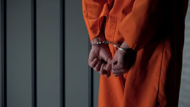 Prisoner with handcuffed arms behind back, another jail transfer, criminal