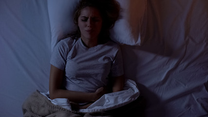 Female holding hands on stomach suffering from abdominal pain, food poisoning