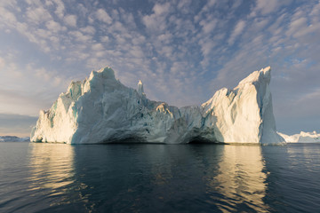 Fototapeta na wymiar Nature and landscapes of Greenland or Antarctica. Travel on the ship among ices. Studying of a phenomenon of global warming Ices and icebergs of unusual forms and colors Beautiful midnight sun on ship