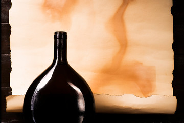 A squat bottle of wine against the backdrop of a papyrus scroll