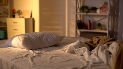 Fototapeta na wymiar Messy bed, white pillow with blanket lying on bed unmade, oversleeping concept