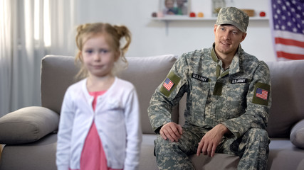 Fototapeta premium Smiling father military officer looking at grown up daughter with pride, us flag