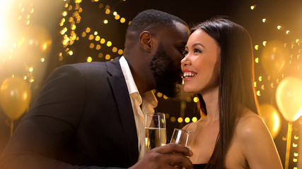 Afro-american gentleman whispering compliments to beautiful lady at party, flirt