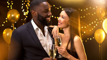 Sexy asian female flirting with afro-american male, holding glasses of beverage