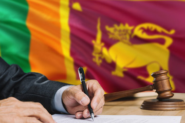 Judge writing on paper in courtroom with Sri Lanka flag background. Wooden gavel of equality theme...