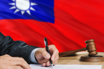 Judge writing on paper in courtroom with Taiwan flag background. Wooden gavel of equality theme and legal concept.